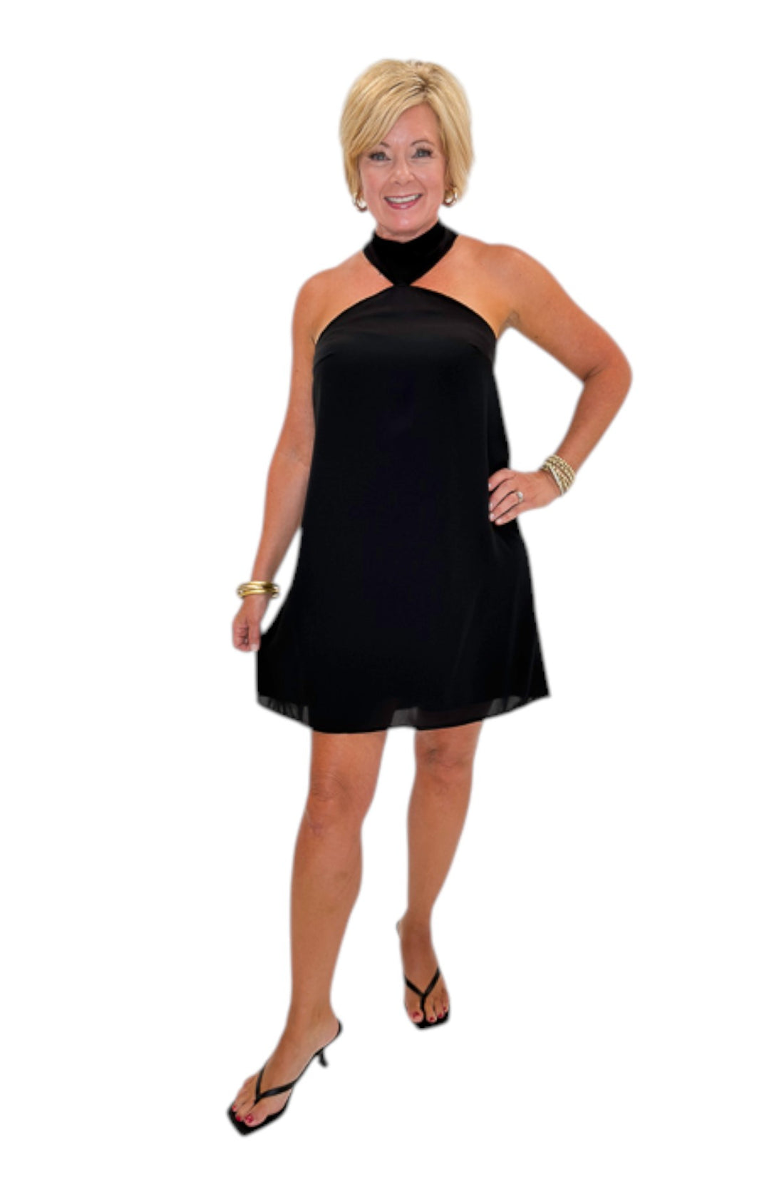 Front view of woman wearing Swagger Boutique’s Black Halter Neck Mini Dress with heels against white studio background.