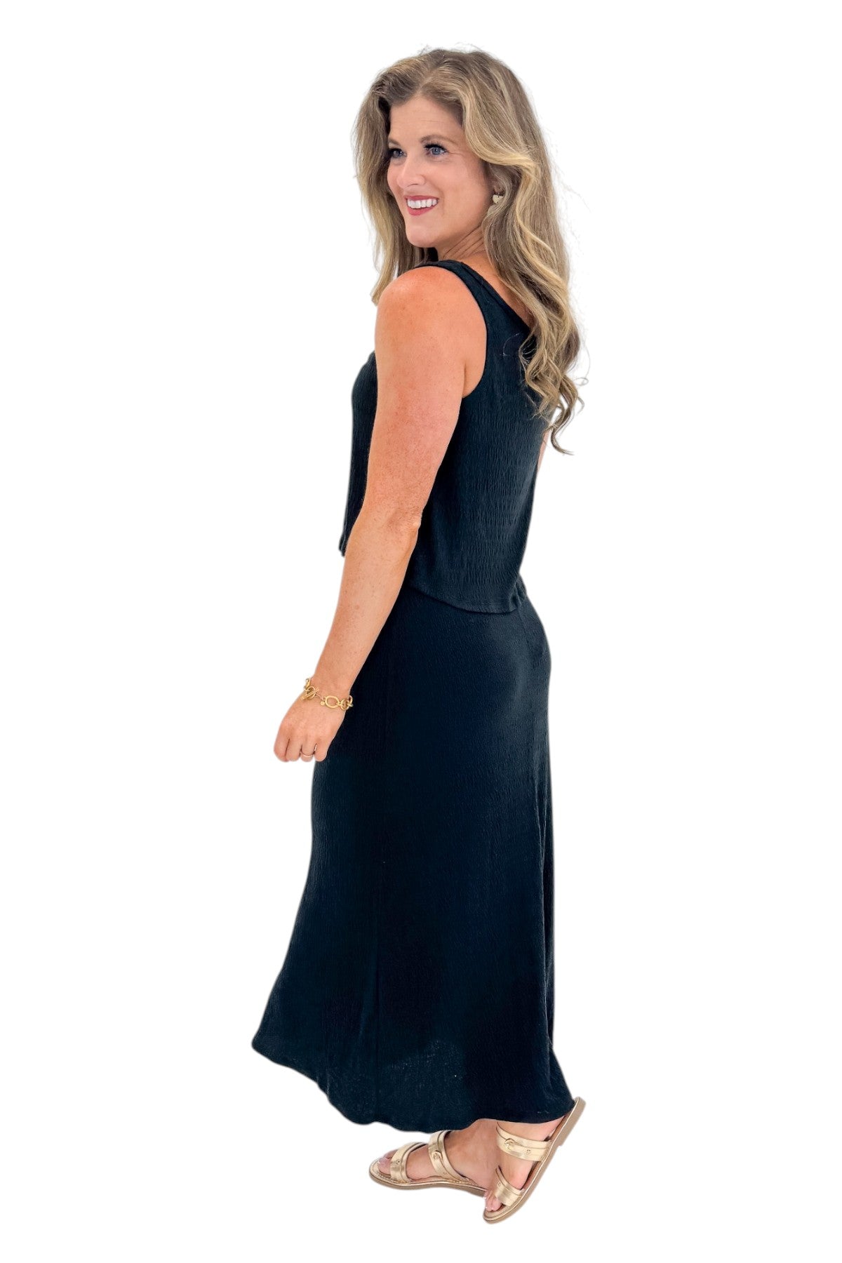 Side view of woman wearing Swagger Boutique’s Black Joanna Tank by Z Supply with Black Idris Maxi Skirt by Z Supply against white studio background.