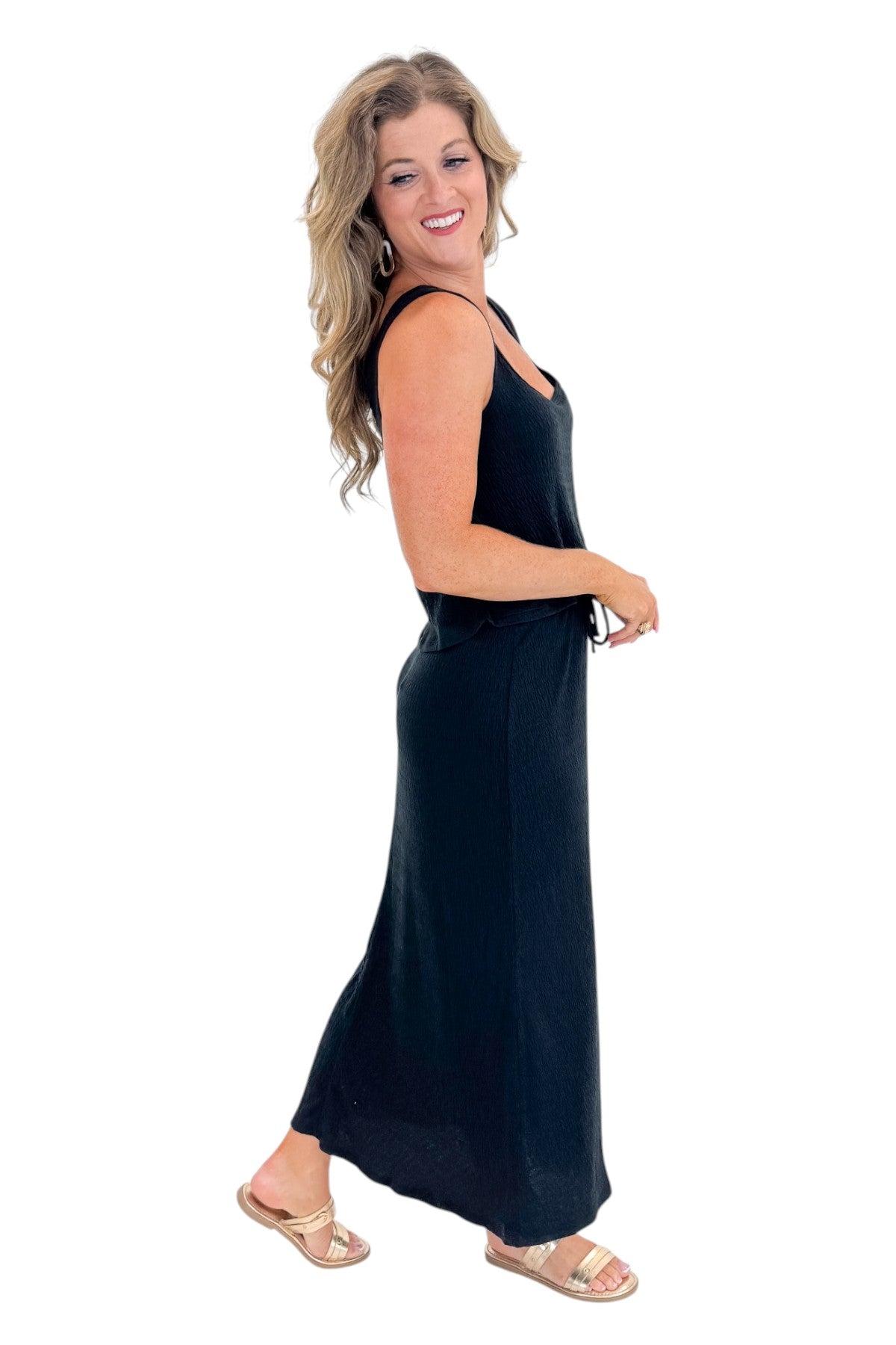 Side view of woman wearing Swagger Boutique’s Black Joanna Tank by Z Supply with Black Idris Maxi Skirt by Z Supply against white studio background.