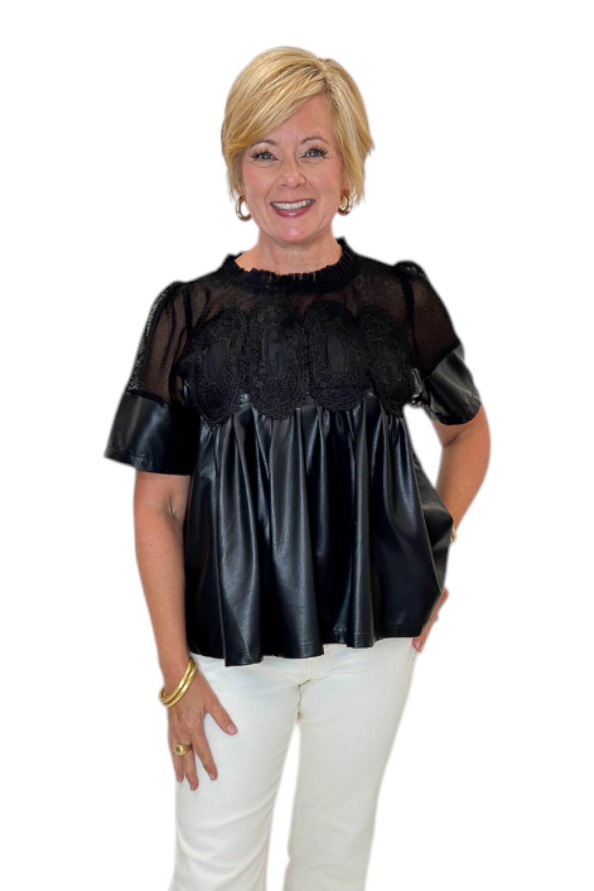 Front view of woman wearing Swagger Boutique’s Black Lace Applique Faux Leather Top with jeans against white studio background.