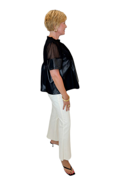 Side view of woman wearing Swagger Boutique’s Black Lace Applique Faux Leather Top with jeans against white studio background.