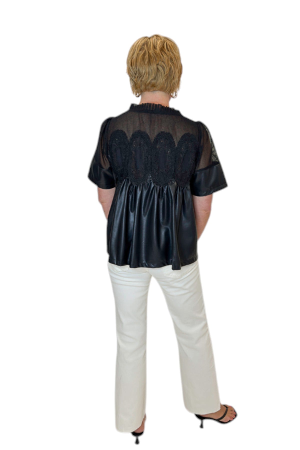 Back view of woman wearing Swagger Boutique’s Black Lace Applique Faux Leather Top with jeans against white studio background.