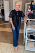 Front view of woman wearing Swagger Boutique’s Black Lace Applique Faux Leather Top with jeans standing at the store.