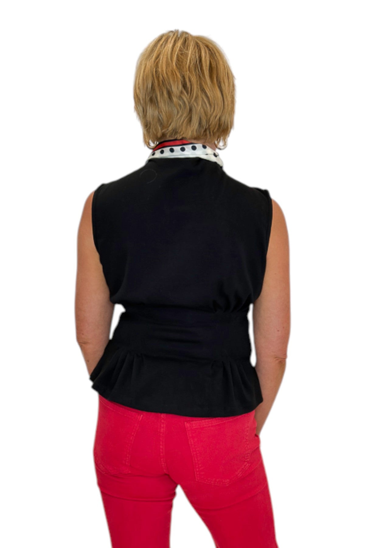 Back view of woman wearing Swagger Boutique’s Black Mock Neck Pleat Waist Top by Entro with skirt against white studio background.
