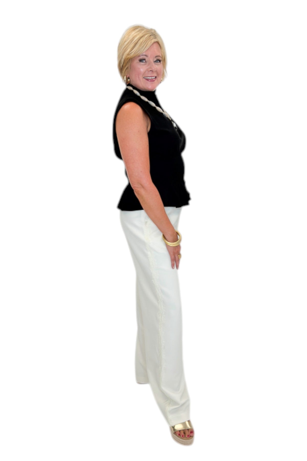 Side view of woman wearing Swagger Boutique’s Black Mock Neck Pleat Waist Top by Entro with skirt against white studio background.