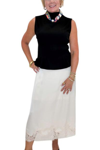 Front detail view of woman wearing Swagger Boutique’s Black Mock Neck Pleat Waist Top by Entro with skirt against white studio background.