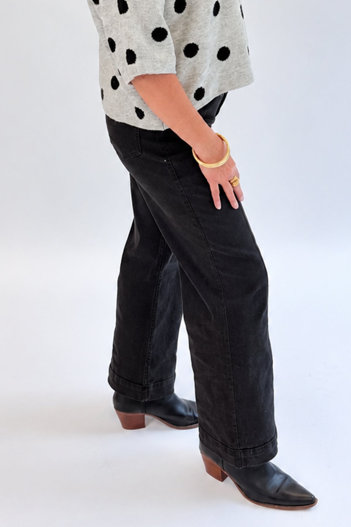 Side view of woman wearing Swagger Boutique’s Black Pintuck Jeans by Risen with sweater against white studio background.