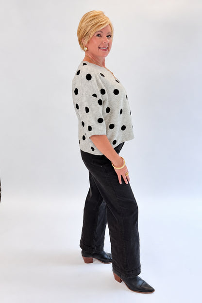 Side view of woman wearing Swagger Boutique’s Black Pintuck Jeans by Risen with sweater against white studio background.
