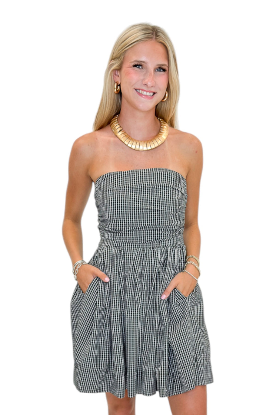 Front view of woman wearing Swagger Boutique’s Black Plaid Strapless Mini Dress with boots against white studio background.