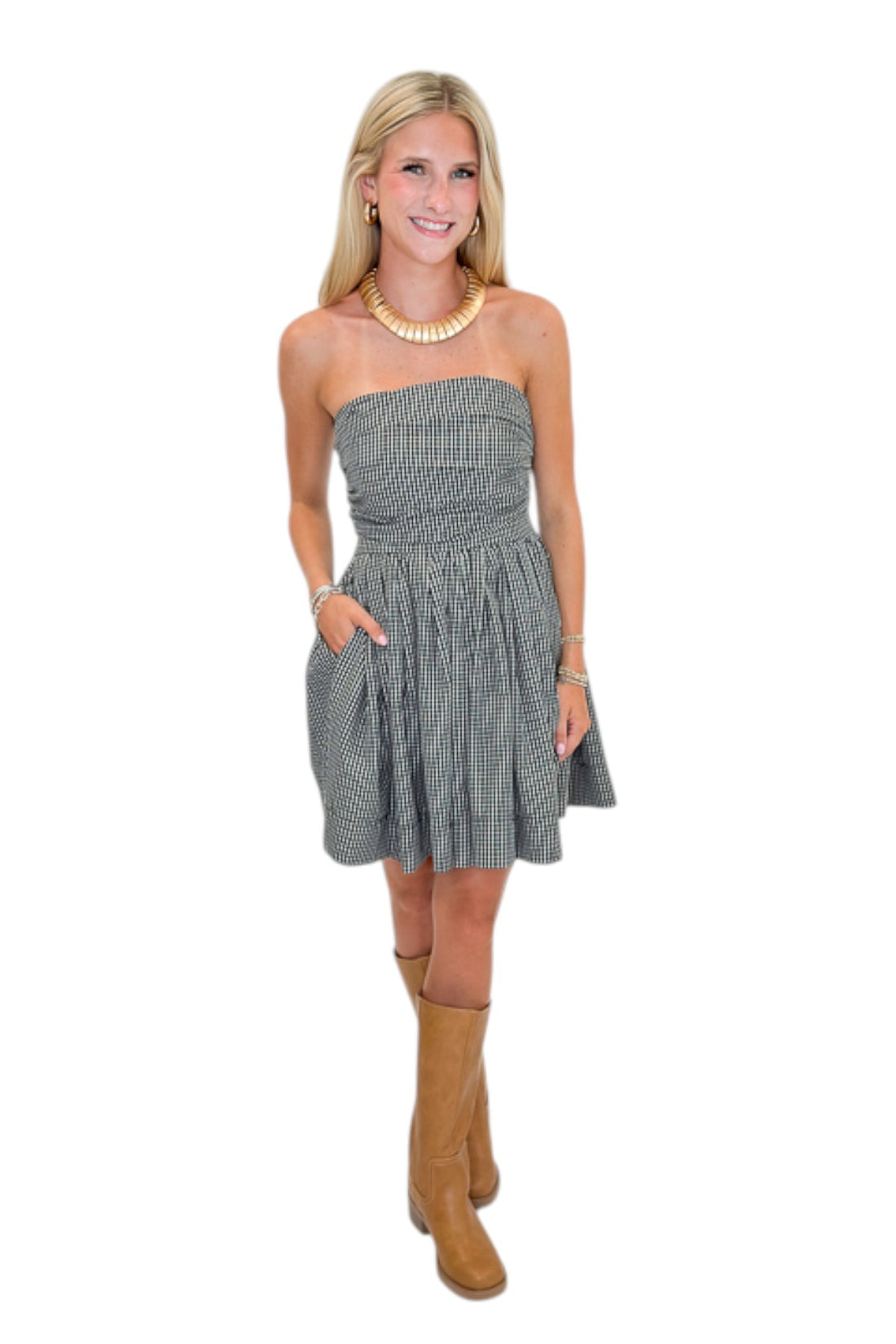 Front view of woman wearing Swagger Boutique’s Black Plaid Strapless Mini Dress with boots against white studio background.
