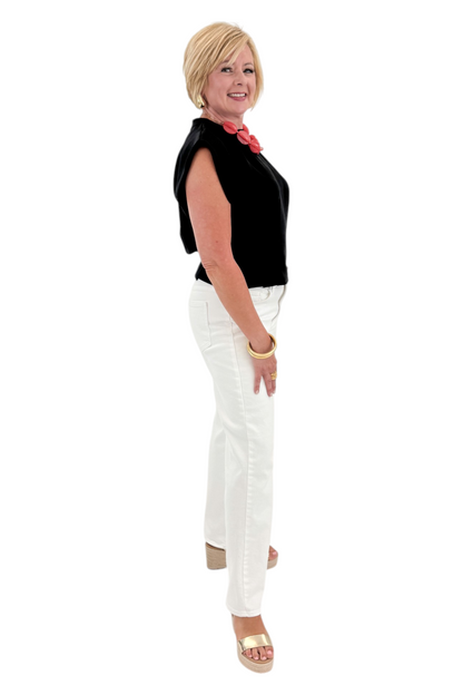 Side view of woman wearing Swagger Boutique’s Black Pleat Detail Tank with jeans against white studio background.