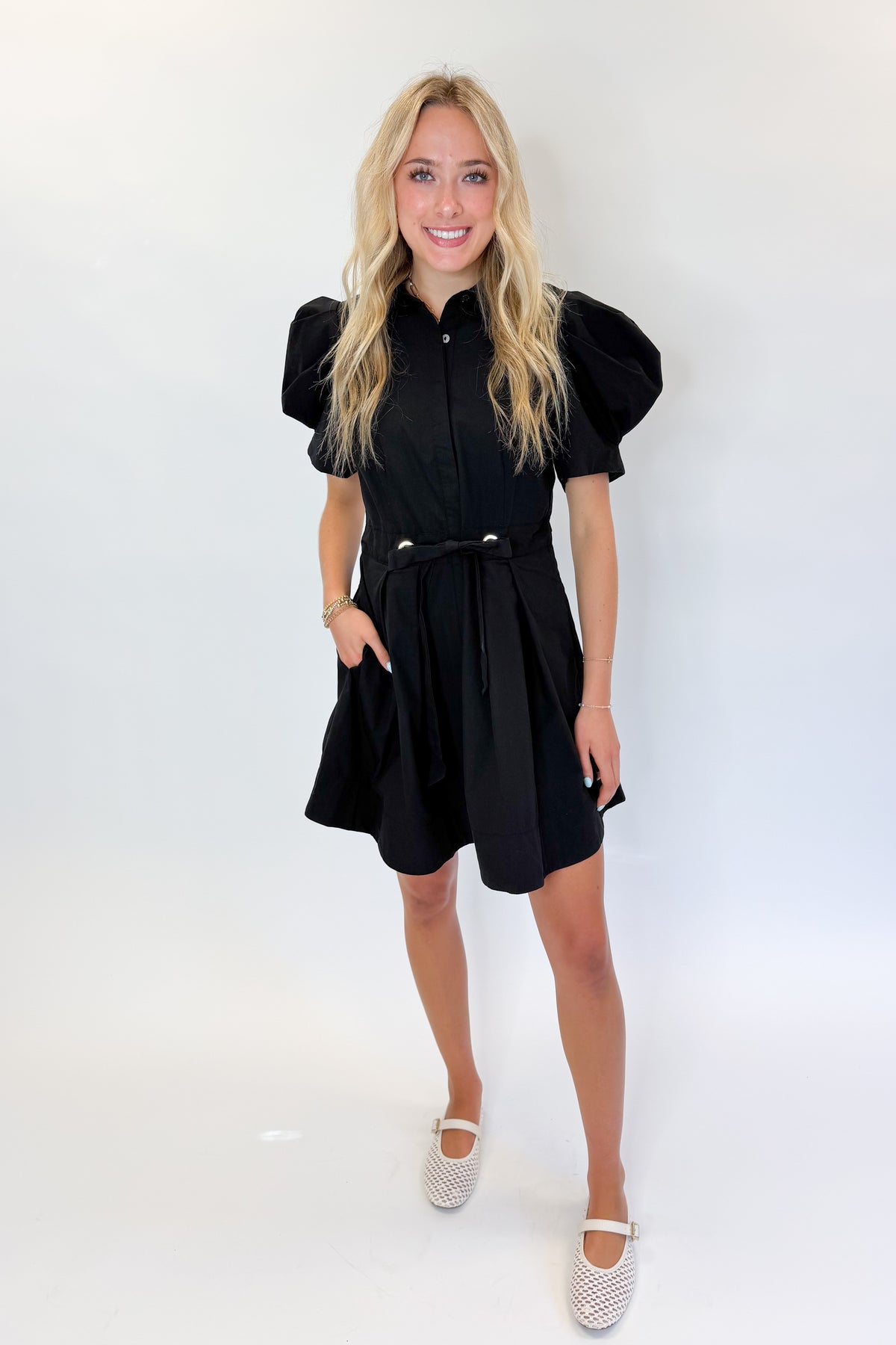 Front view of woman wearing Swagger Boutique’s Black Puff Sleeve Mini Dress by Entro against white studio background.