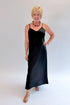 Front view of woman wearing Swagger Boutique’s Black Satin Dress with heels against white studio background.