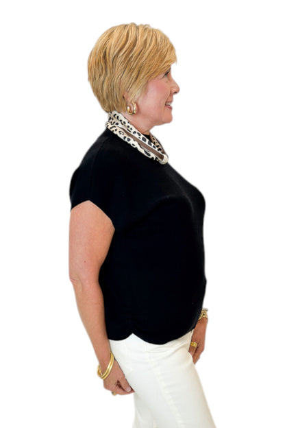 Side view of woman wearing Swagger Boutique’s Black Shirred Cap Sleeve Sweater with jeans against white studio background.