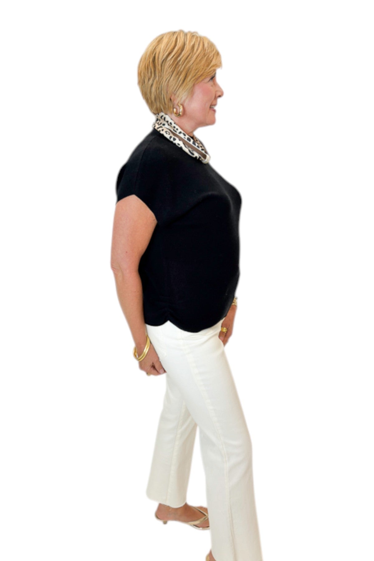 Side view of woman wearing Swagger Boutique’s Black Shirred Cap Sleeve Sweater with jeans against white studio background.