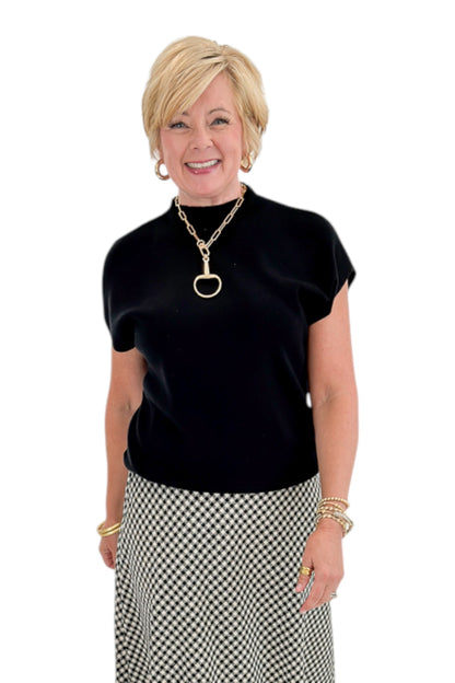 Front view of woman wearing Swagger Boutique’s Black Shirred Cap Sleeve Sweater with skirt against white studio background.