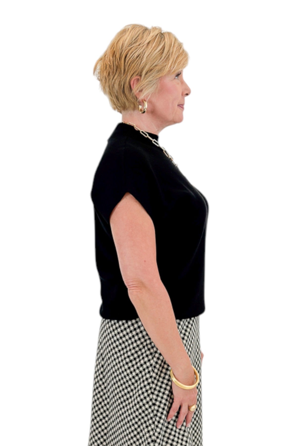 Side view of woman wearing Swagger Boutique’s Black Shirred Cap Sleeve Sweater with skirt against white studio background.