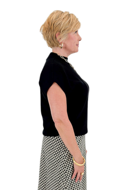 Side view of woman wearing Swagger Boutique’s Black Shirred Cap Sleeve Sweater with skirt against white studio background.