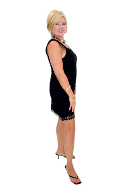 Side view of woman wearing Swagger Boutique’s Black Sleeveless Lace Mini Dress by Entro with heels against white studio background.