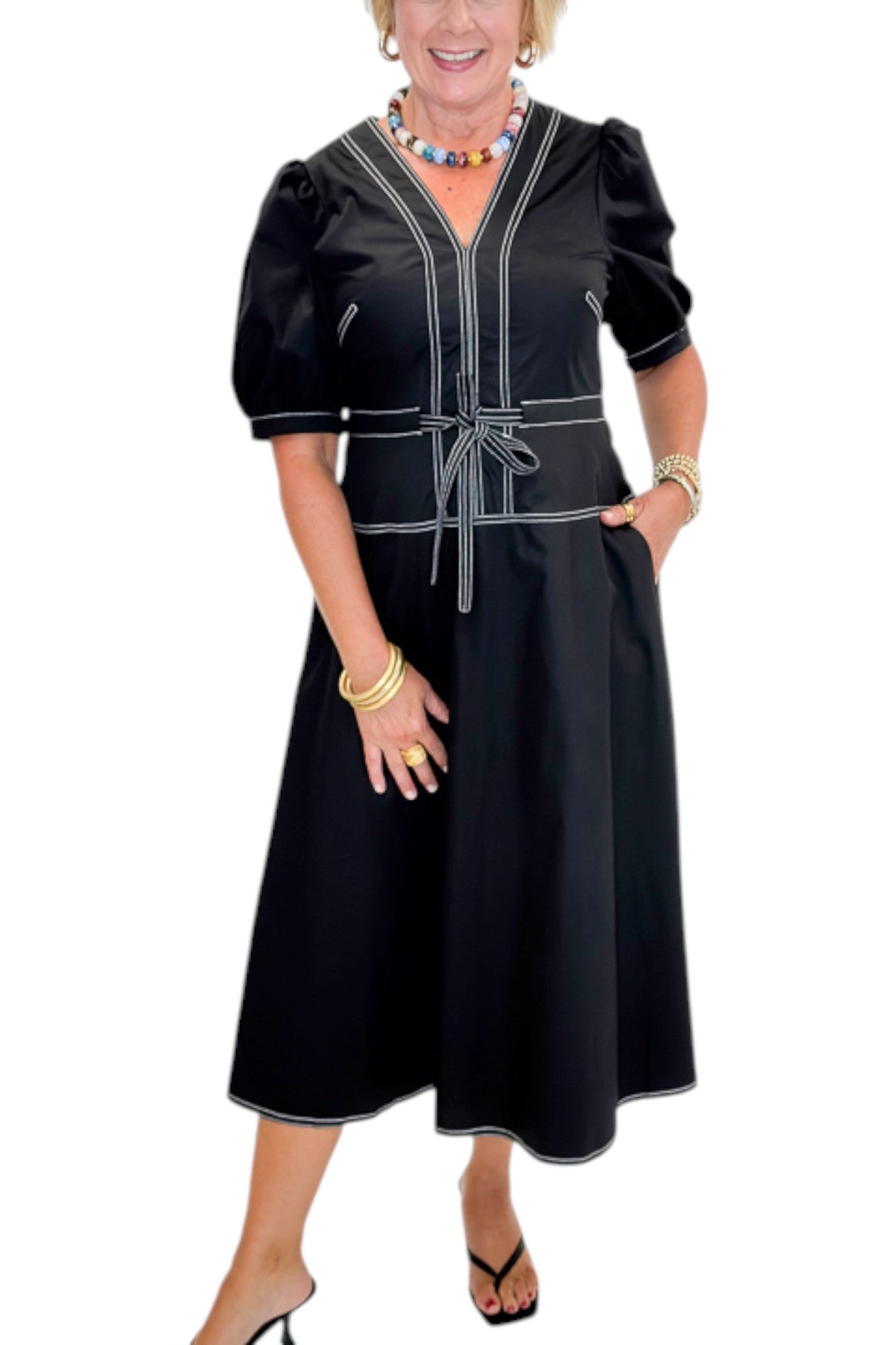 Front detail view of woman wearing Swagger Boutique’s Black Stitch Midi Dress with heels against white studio background.