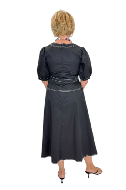 Back view of woman wearing Swagger Boutique’s Black Stitch Midi Dress with heels against white studio background.