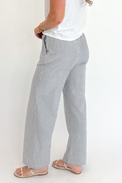 Side detail view of woman wearing Swagger Boutique’s Black Striped Wide Leg Pants with Junie White Tee by Z Supply against white studio background.