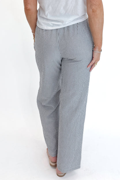 Back detail view of woman wearing Swagger Boutique’s Black Striped Wide Leg Pants with Junie White Tee by Z Supply against white studio background.