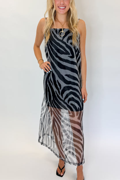 Front detail view of woman wearing Swagger Boutique’s Black Zebra Maxi Dress with heels against white studio background.