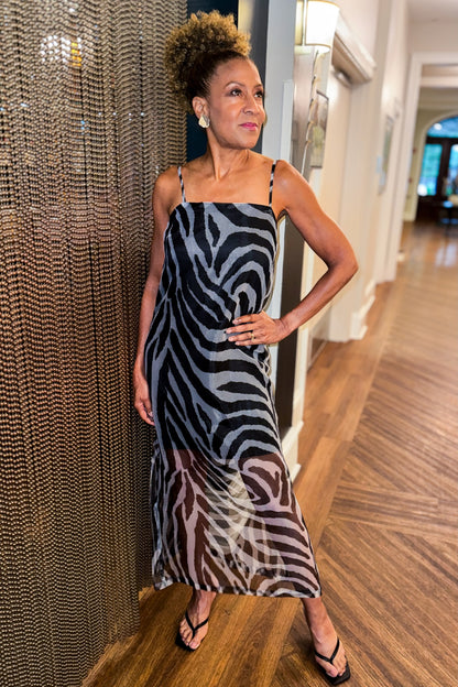 Front view of woman wearing Swagger Boutique’s Black Zebra Maxi Dress with heels standing at an Art Gallery. 