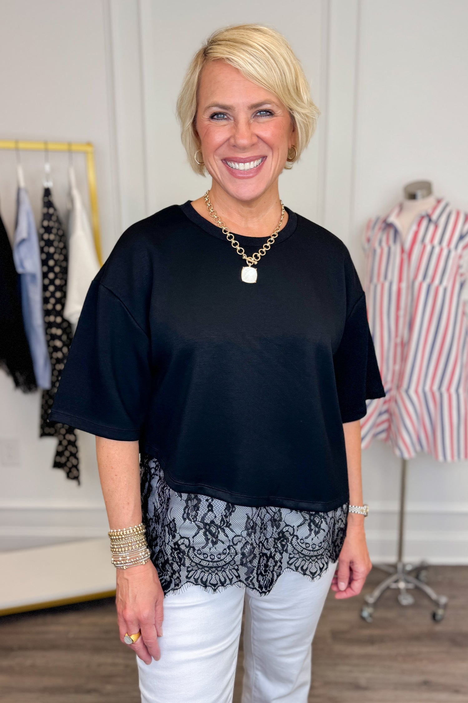 Front view of woman wearing Swagger Boutique’s Black Asymmetrical Lace Hem Top by Entro with jeans against white studio background.