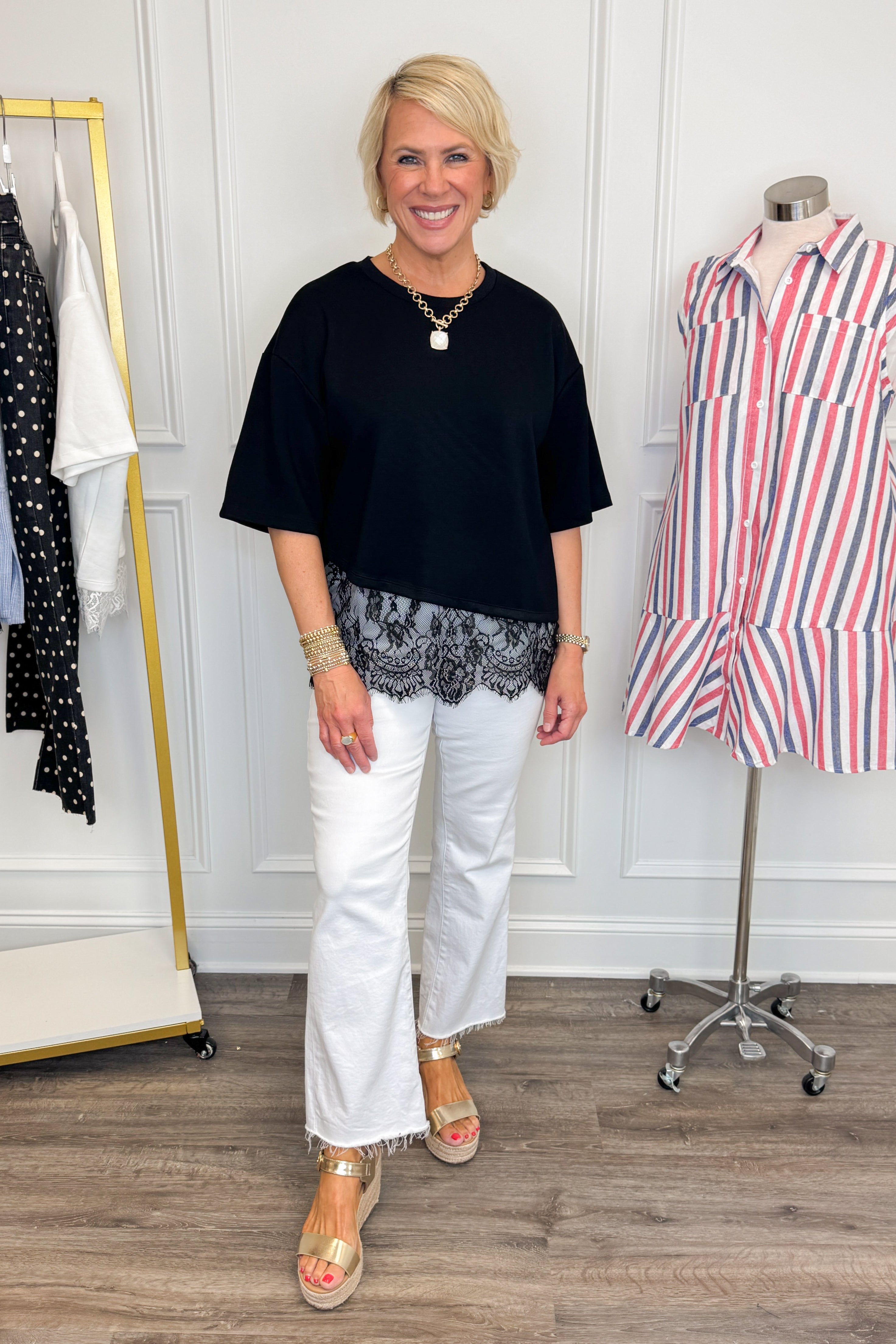 Front view of woman wearing Swagger Boutique’s Black Asymmetrical Lace Hem Top by Entro with jeans against white studio background.