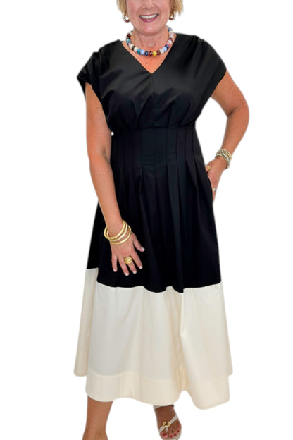 Front detail view of woman wearing Swagger Boutique’s Black &amp; Cream Color Block Midi Dress by Entro with sandals against white studio background.