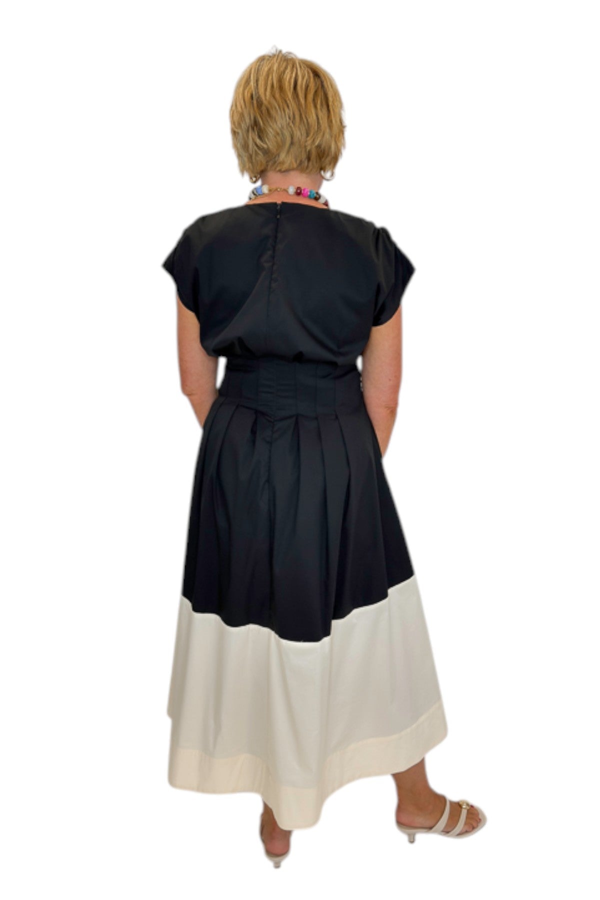 Back view of woman wearing Swagger Boutique’s Black &amp; Cream Color Block Midi Dress by Entro with sandals against white studio background.