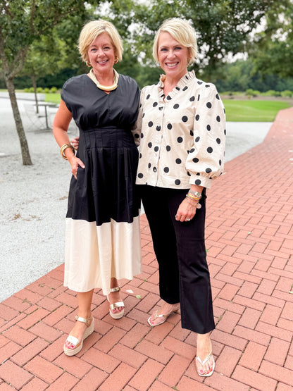 Front view of woman wearing Swagger Boutique’s Black and Cream Color Block Midi Dress and woman wearing Cream and Black Polka Dot 3/4 Sleeve Top with Kelsey Black Jeans in an outdoor scenery. 