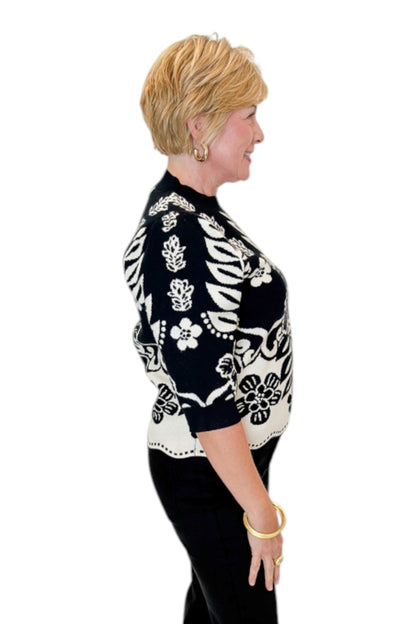 Side view of woman wearing Swagger Boutique’s Black &amp; Cream Printed Short Sleeve Sweater by THML with jeans against white studio background.