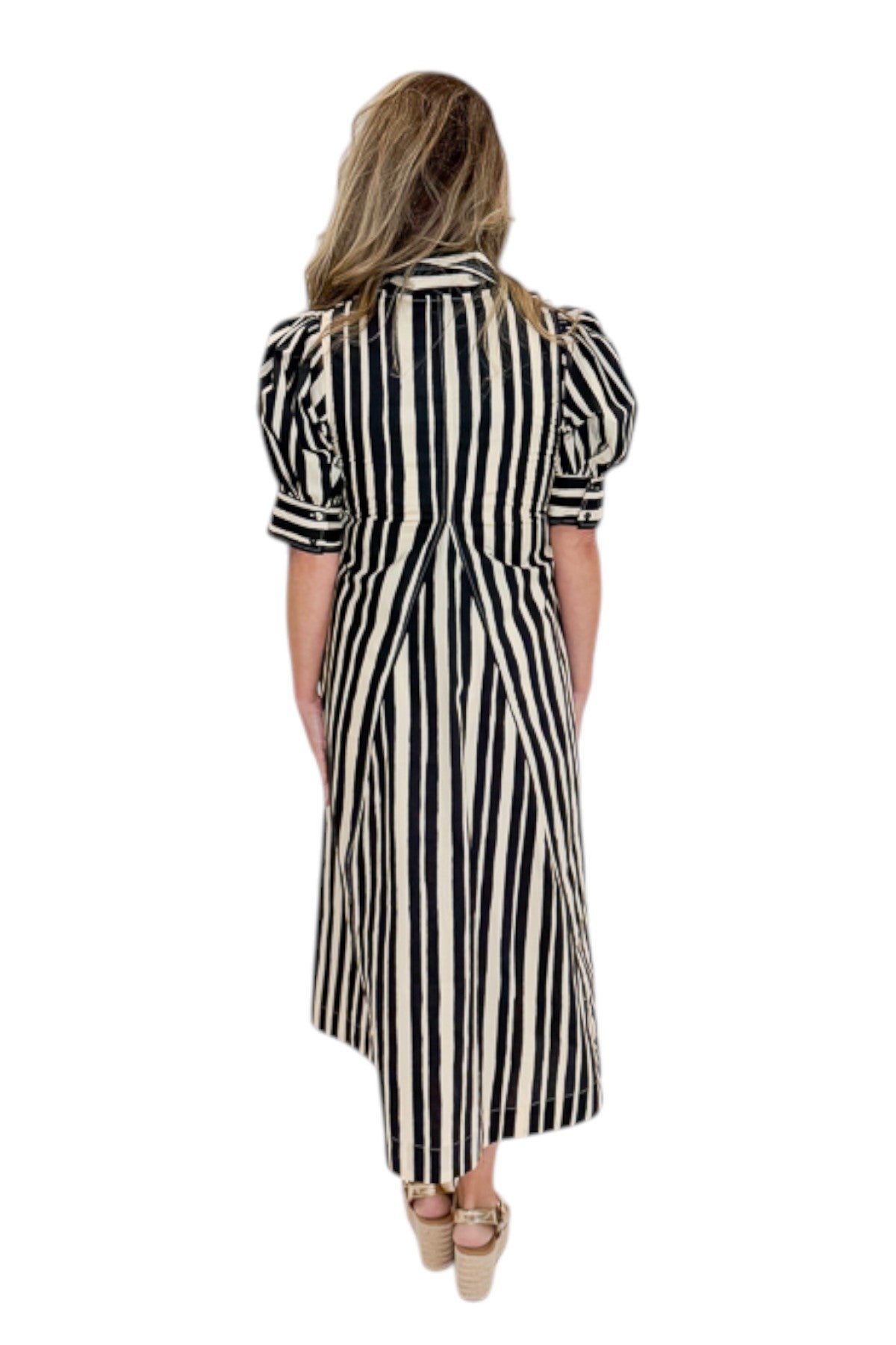 Back view of woman wearing Swagger Boutique’s Black &amp; Cream Striped Midi Dress with sandals against white studio background.