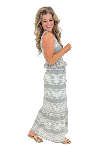 Side view of woman wearing Swagger Boutique’s Black &amp; Cream Striped Peplum Tank with matching tiered skirt against white studio background.