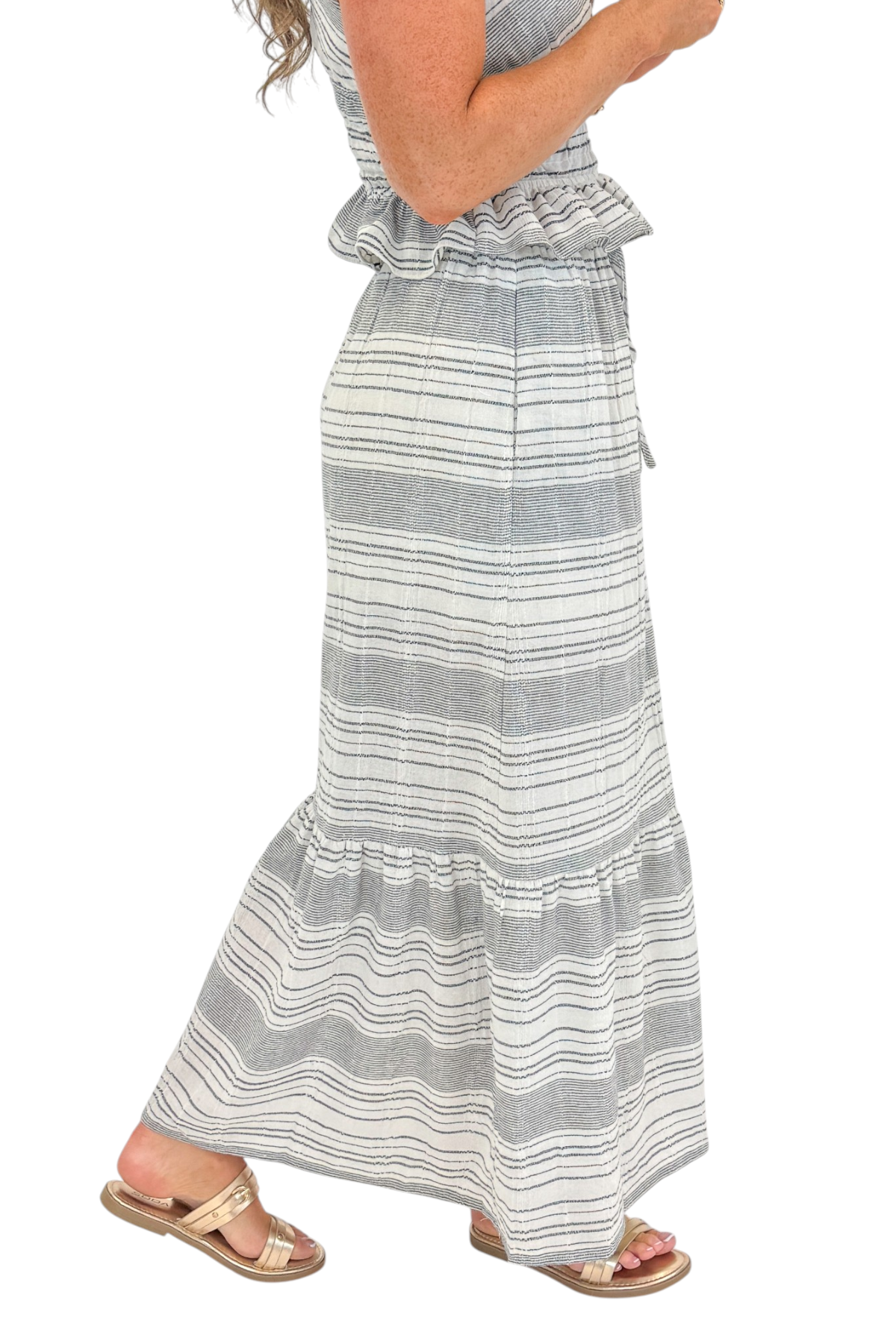 Side detail view of woman wearing Swagger Boutique’s Black &amp; Cream Striped Peplum Tank with matching tiered skirt against white studio background.