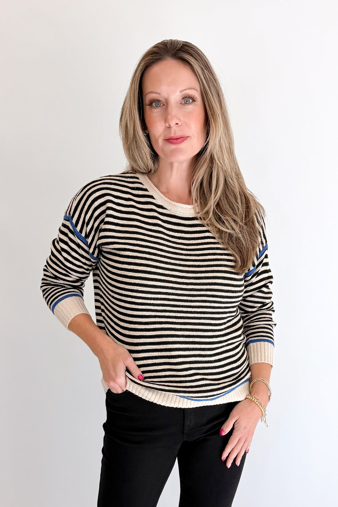 Front view of woman wearing Swagger Boutique’s Black &amp; Cream Striped Sweater With Blue Accent with Kelsey Black Jeans against white studio background.