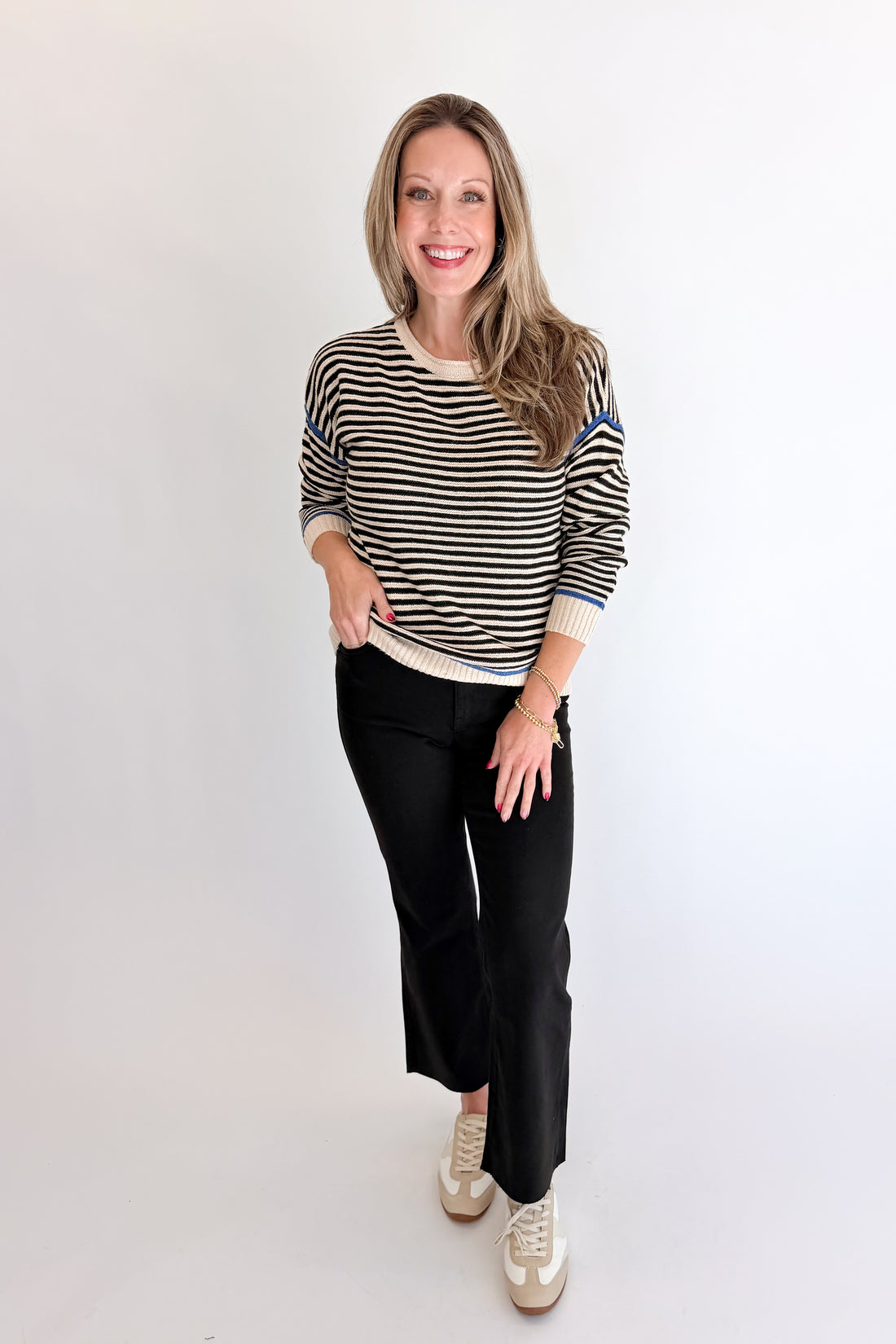 Front view of woman wearing Swagger Boutique’s Black &amp; Cream Striped Sweater With Blue Accent with Kelsey Black Jeans against white studio background.