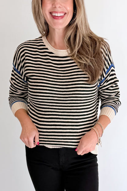 Front detail view of woman wearing Swagger Boutique’s Black &amp; Cream Striped Sweater With Blue Accent with Kelsey Black Jeans against white studio background.