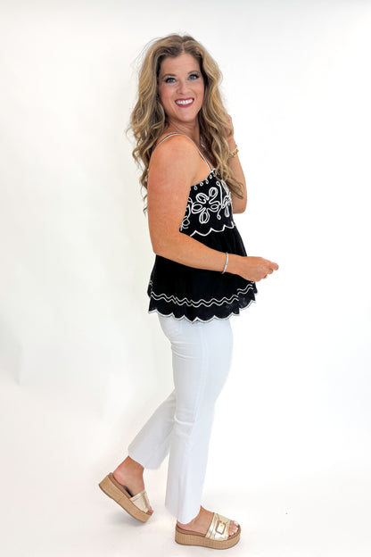 Side view of woman wearing Swagger Boutique’s Black &amp; Ivory Embroidered Tank with jeans against white studio background.