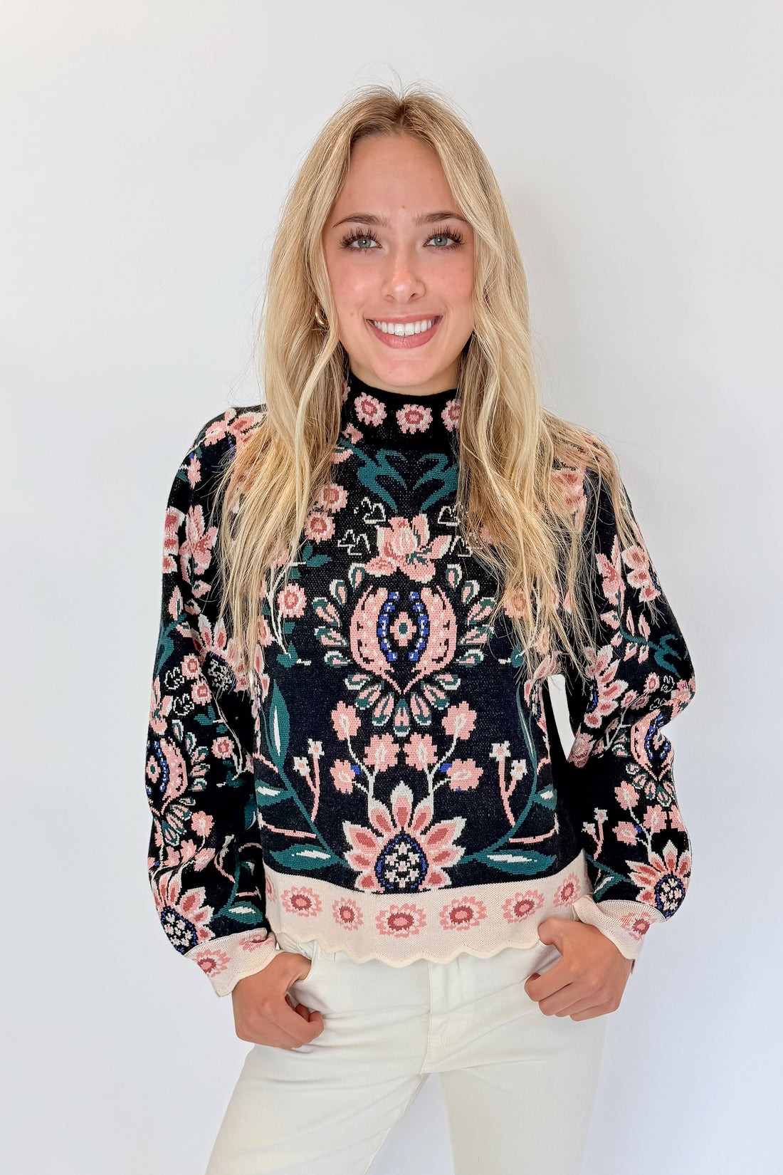 Front view of woman wearing Swagger Boutique’s Black &amp; Multi Floral Print Sweater by THML with jeans against white studio background.