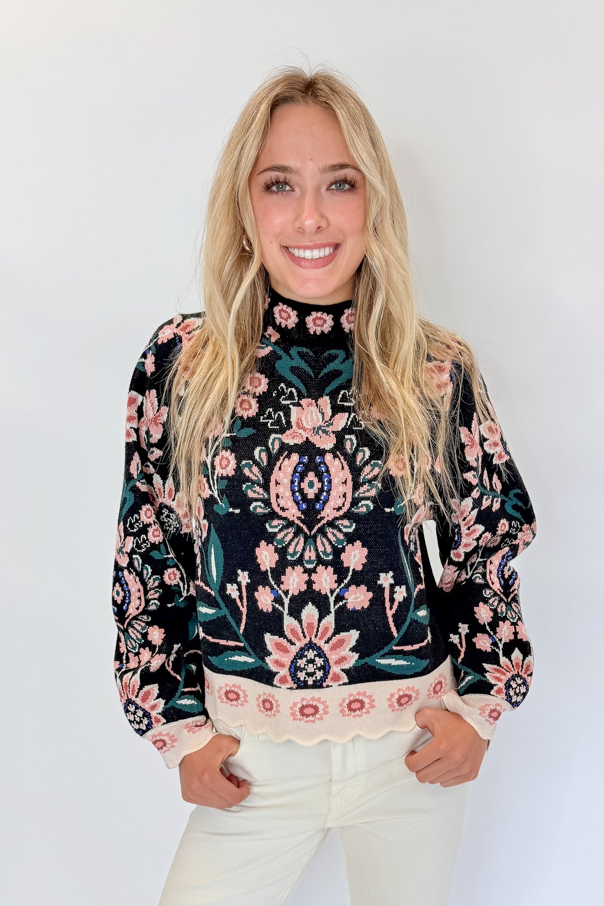Front view of woman wearing Swagger Boutique’s Black &amp; Multi Floral Print Sweater by THML with jeans against white studio background.
