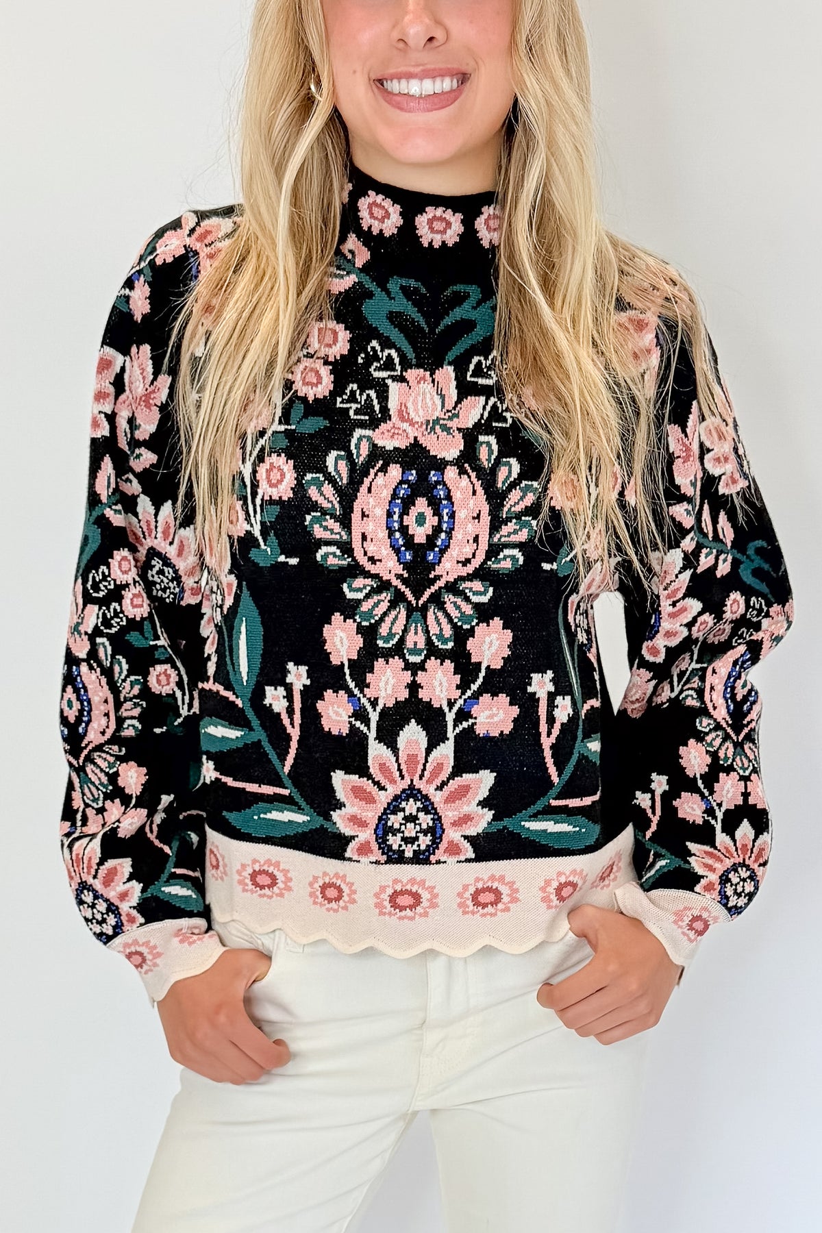 Front detail view of woman wearing Swagger Boutique’s Black &amp; Multi Floral Print Sweater by THML with jeans against white studio background.