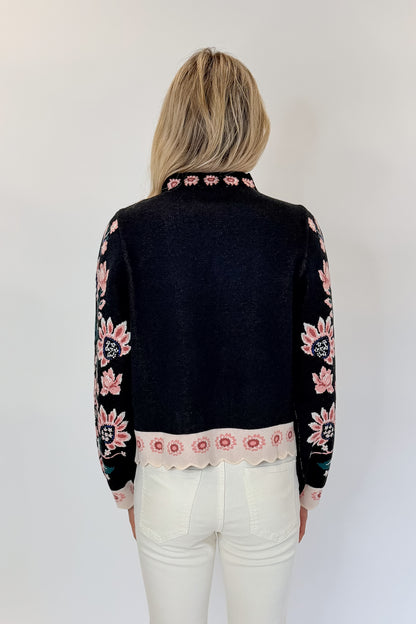 Back view of woman wearing Swagger Boutique’s Black &amp; Multi Floral Print Sweater by THML with jeans against white studio background.
