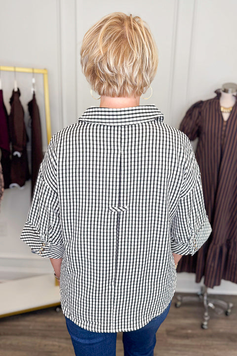 Back view of woman wearing Swagger Boutique’s Black &amp; White Gingham Collared Top by Entro with jeans against white studio background.