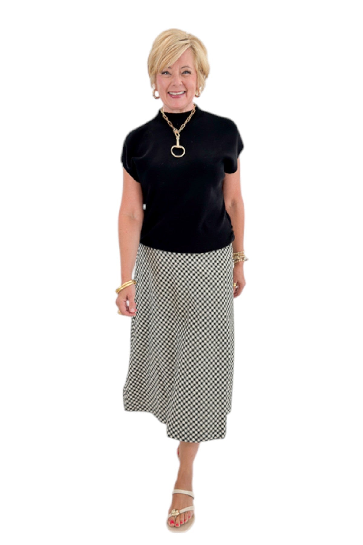 Front view of woman wearing Swagger Boutique’s Black Shirred Cap Sleeve Sweater with Black &amp; White Plaid Midi Skirt against white studio background.