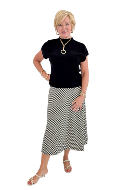 Front view of woman wearing Swagger Boutique’s Black Shirred Cap Sleeve Sweater with Black &amp; White Plaid Midi Skirt against white studio background.