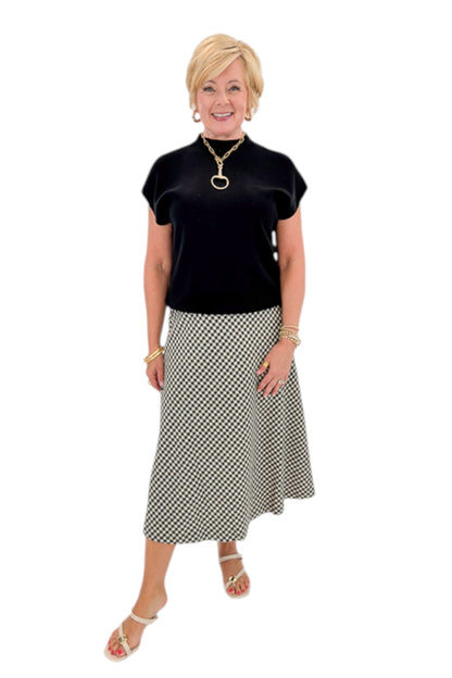 Front view of woman wearing Swagger Boutique’s Black Shirred Cap Sleeve Sweater with Black &amp; White Plaid Midi Skirt against white studio background.